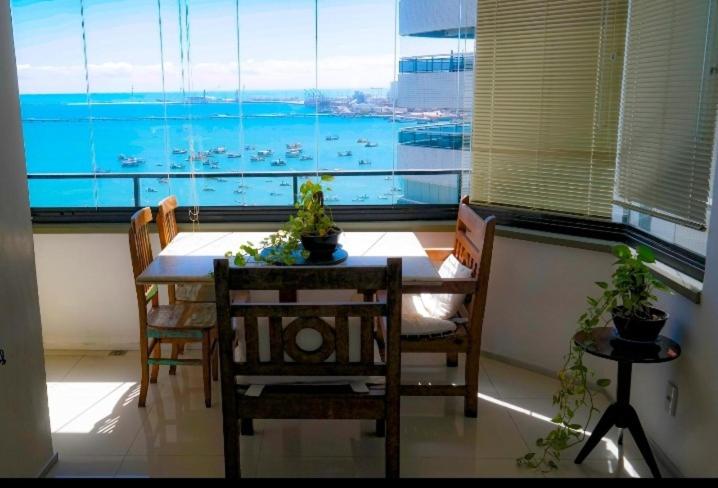 une salle à manger avec une table, des chaises et une grande fenêtre dans l'établissement Flat Beira Mar Golden Fortaleza, à Fortaleza