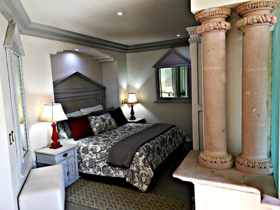 een slaapkamer met een bed en 2 grote zuilen bij Hotel Hacienda los Narcisos in San Juan de los Lagos