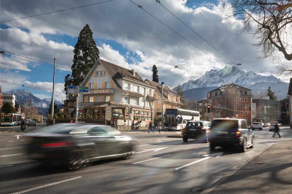 a busy city street with cars and buildings and mountains at Hotel Spatz in Luzern