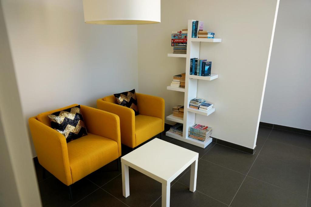 two yellow chairs and a table in a room at Villa Fluisterbos met gratis parking in Ostend