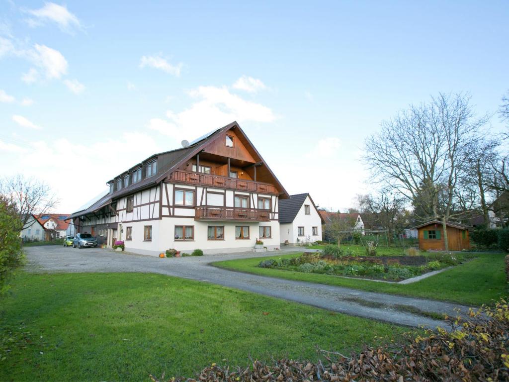 ein großes Holzhaus mit einer Straße davor in der Unterkunft Spacious apartment near Lake Constance with a covered balcony in Ahausen