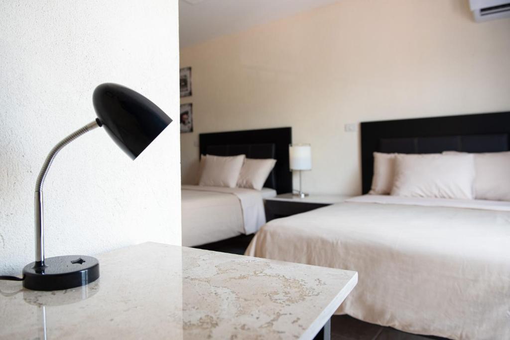 a hotel room with two beds and a desk with a lamp at Hotel Casa Real in Villahermosa