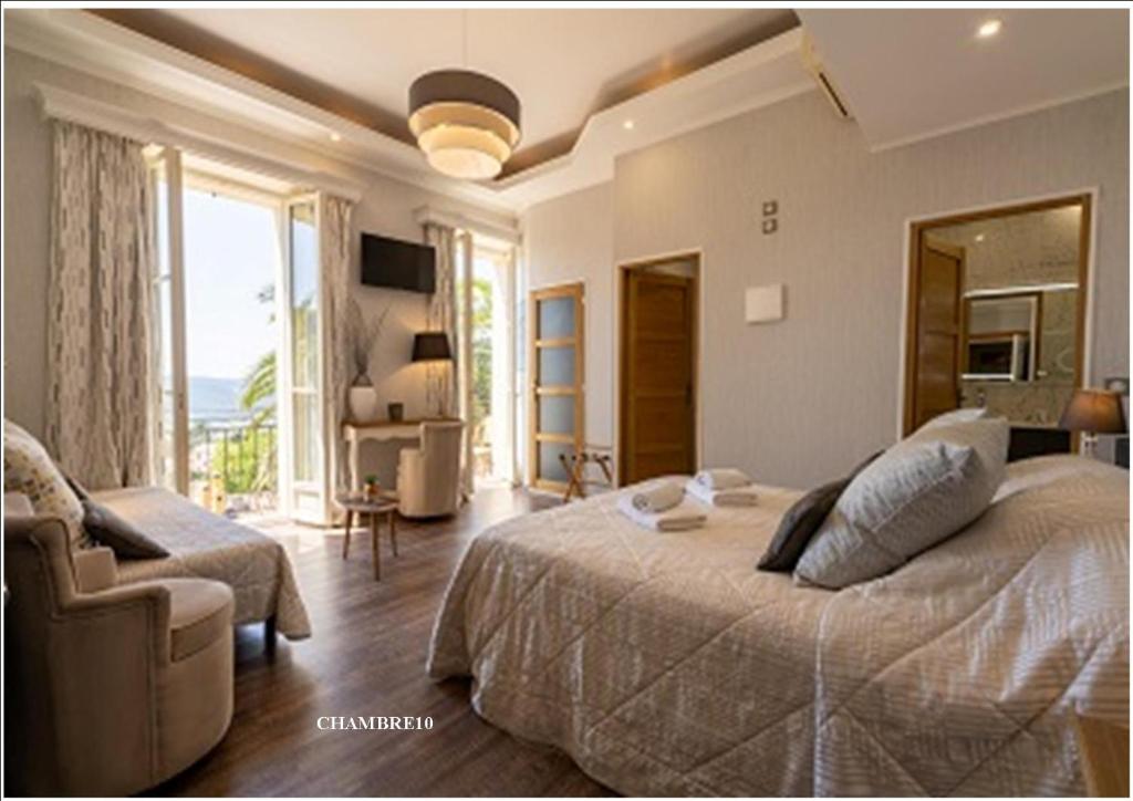 Un dormitorio con una cama y un sofá y una ventana. en Hotel Restaurant Bellevue, en Bormes-les-Mimosas