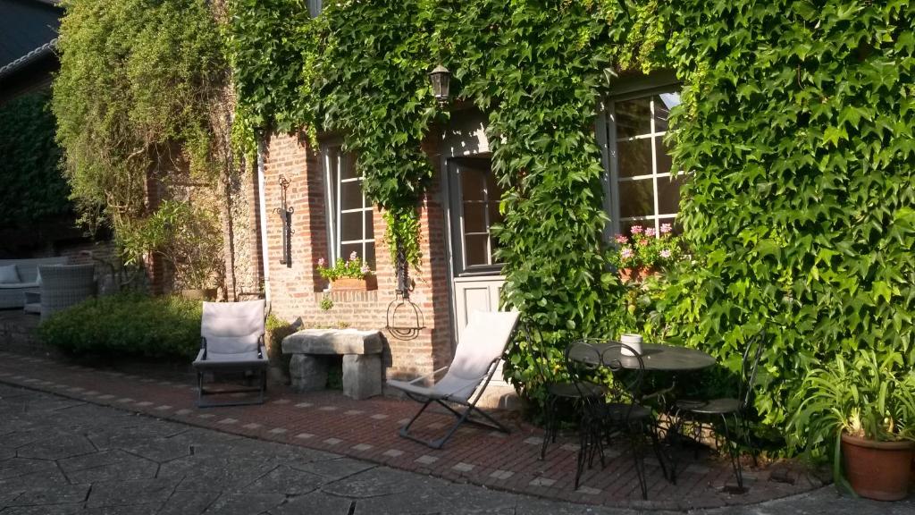 - deux chaises et une table devant le bâtiment dans l'établissement Gite Normandie, à Forges-les-Eaux