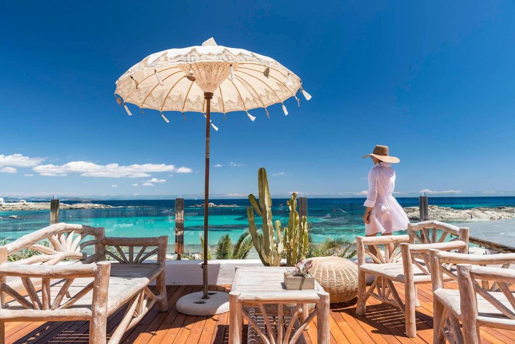 une femme debout sur une terrasse en bois avec un parasol dans l'établissement Hotel Tahiti, à Es Pujols