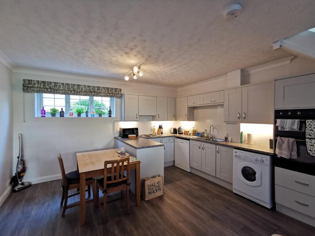 a kitchen with white cabinets and a table and chairs at Chapel Cottage in Oundle