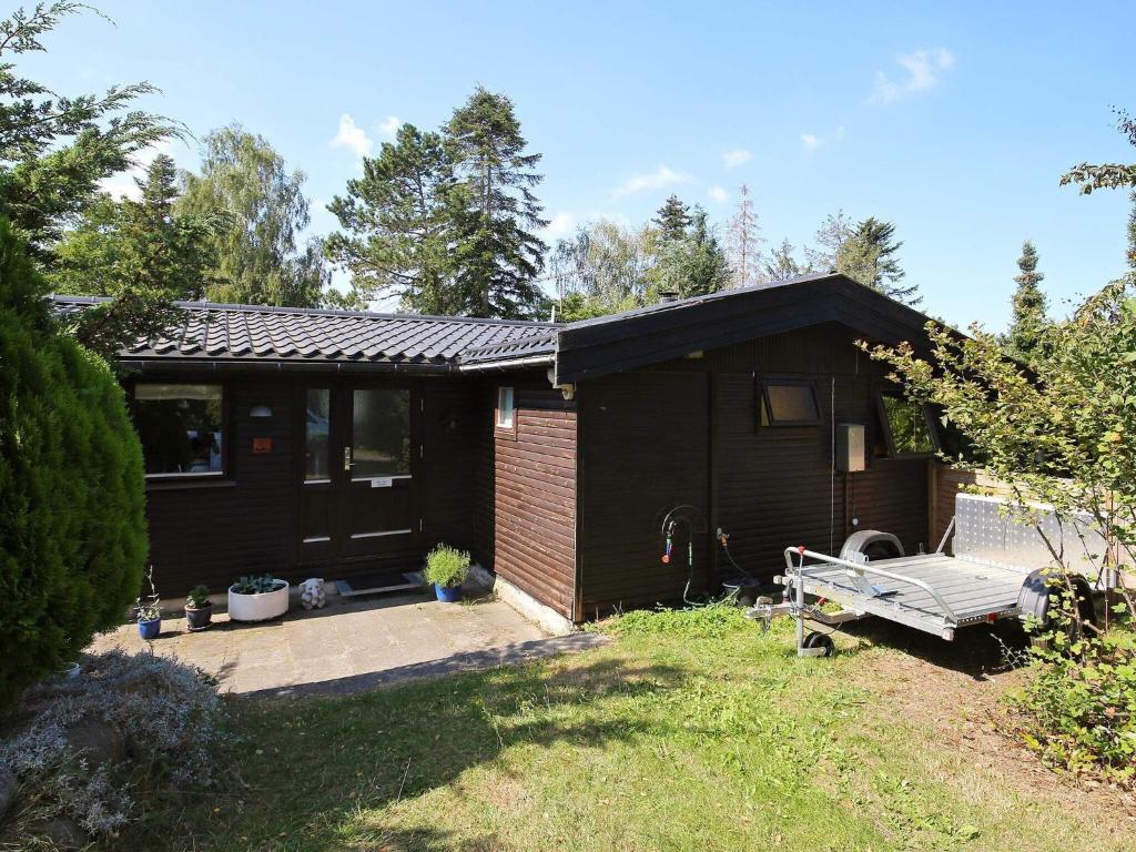 a small black house with a bench in the yard at 8 person holiday home in Holb k in Holbæk