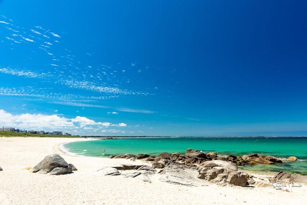 uma praia arenosa com rochas e o oceano em Charmante Maison Bretonne à 2 minutes des plages em Plouescat