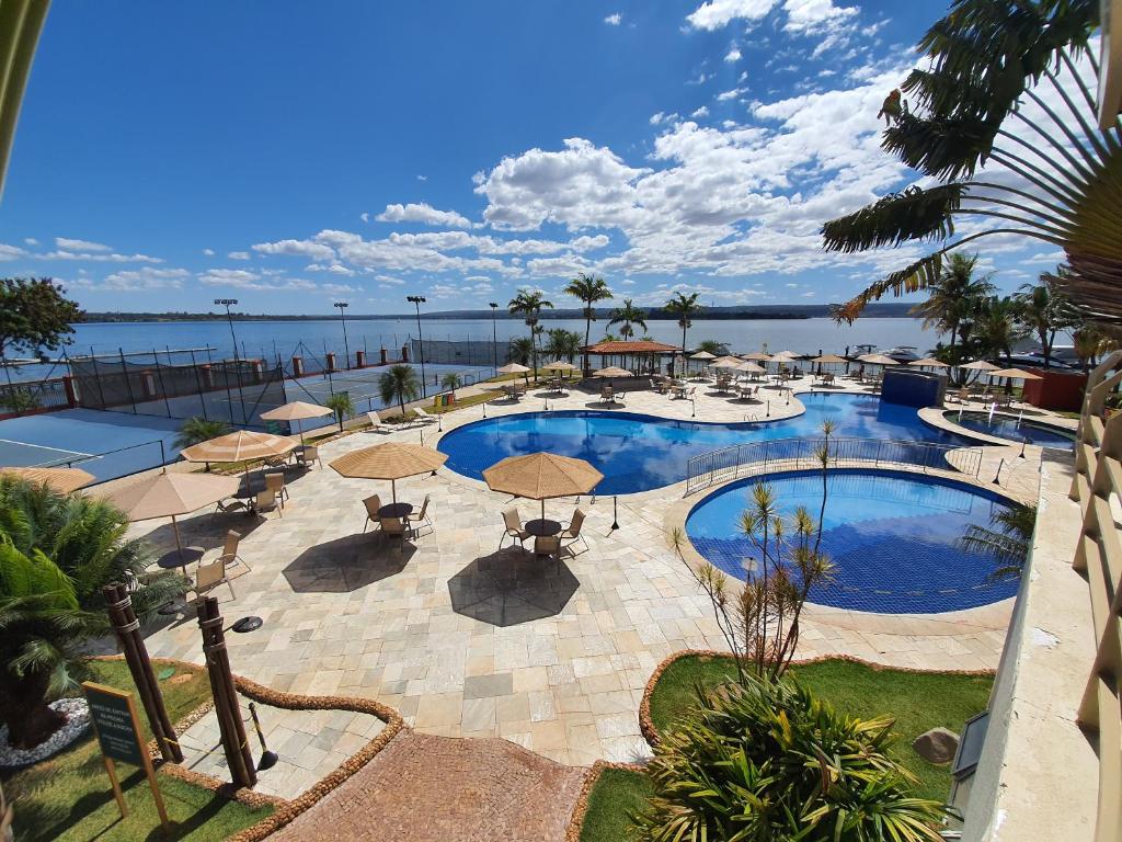 a view of a pool with umbrellas and the water at LAKE SIDE - VISTA DO LAGO By Rei dos Flats in Brasilia