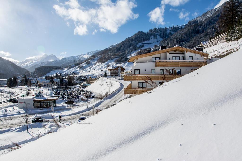 una colina cubierta de nieve con una ciudad en el fondo en Appartements Plaija, en Sankt Anton am Arlberg