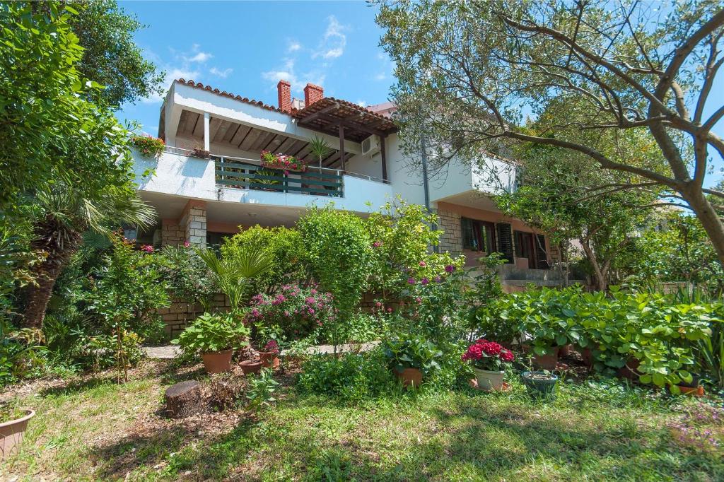 a house with a lot of plants in the yard at Apartments Marin in Novalja