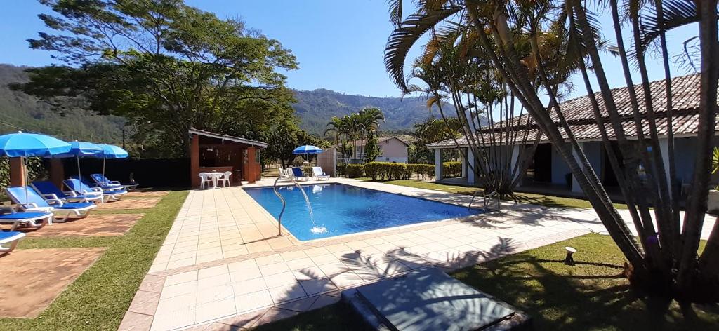 a swimming pool with chairs and umbrellas in a yard at Hotel - Pousada 3 Marias in São Pedro