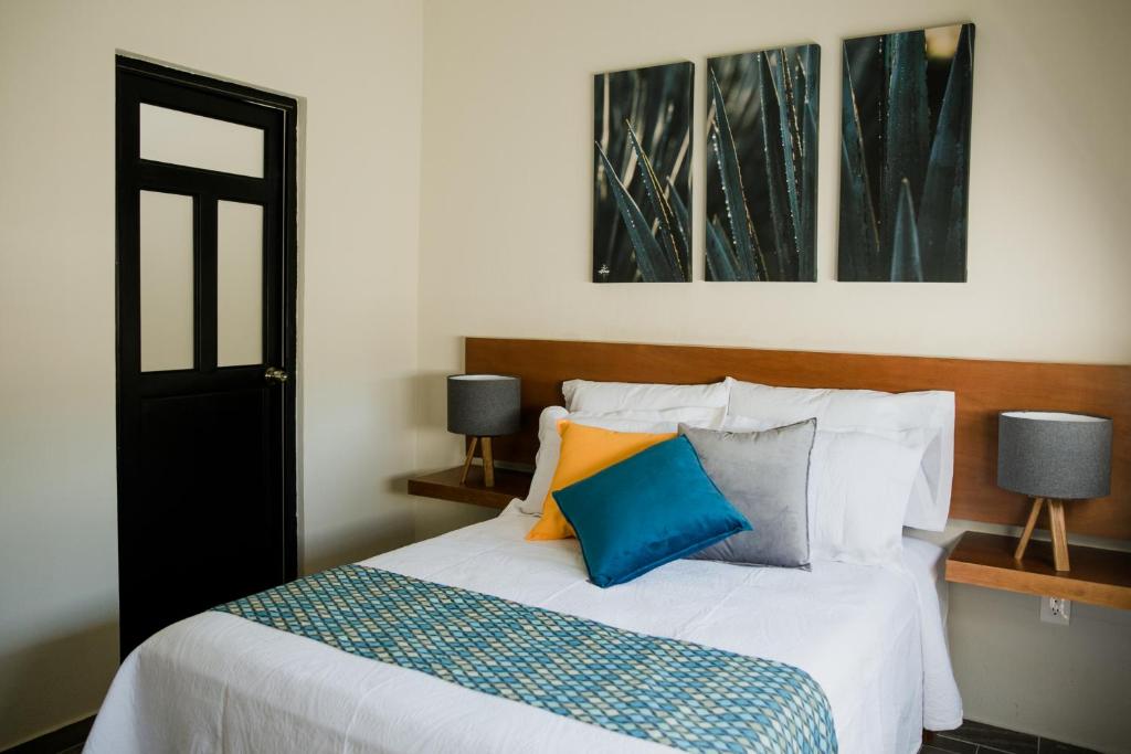 a bedroom with a bed with blue and orange pillows at casa AGAVE x Santiago de Tequila in Tequila