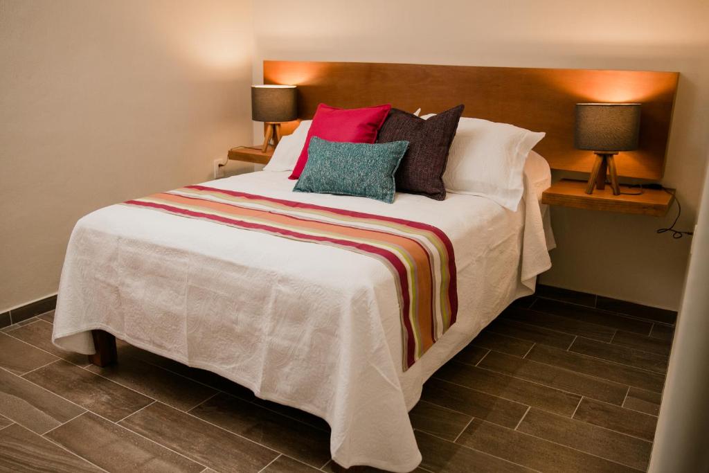 a bedroom with a large white bed with colorful pillows at casa VOLCAN x Santiago de tequila in Tequila