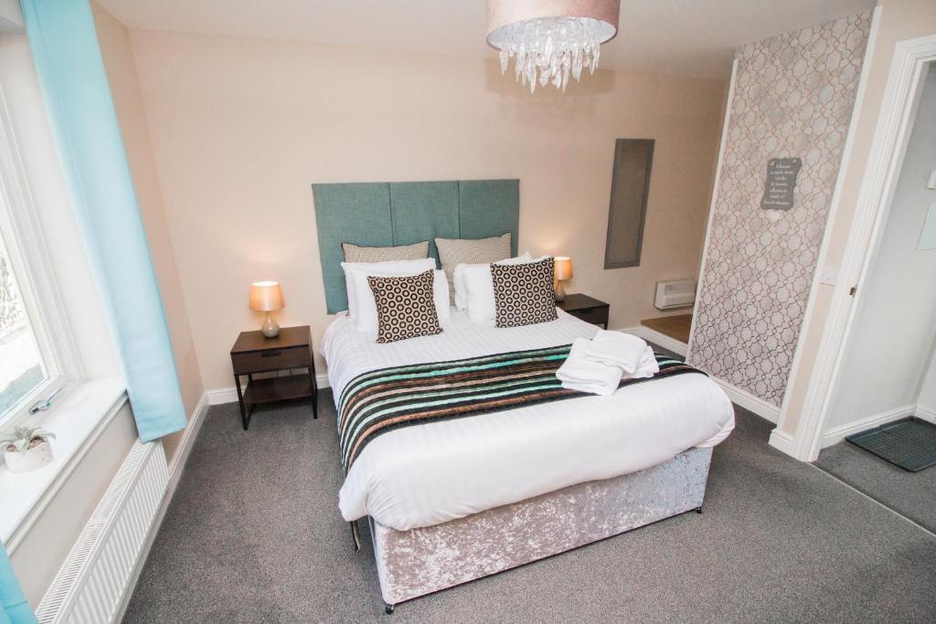 a bedroom with a large bed and a chandelier at Balmaha Lodges and Apartments in Balmaha