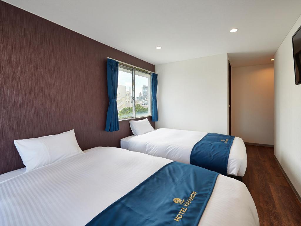 a bedroom with two beds and a window at エナジックホテル山市 Enagic HOTEL YAMAICHI in Naha