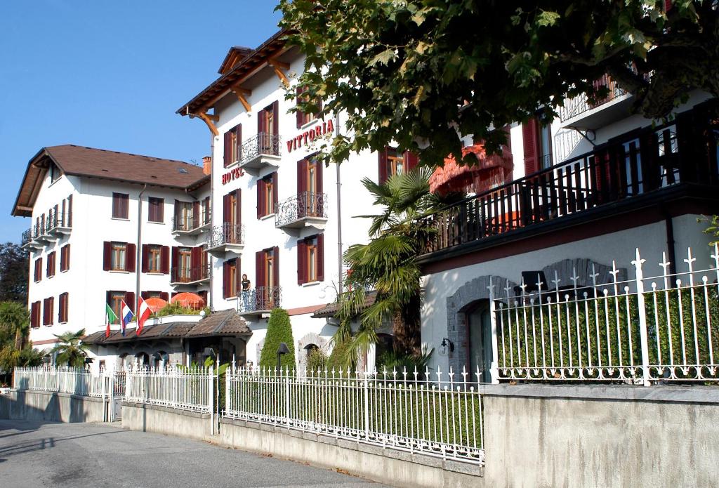 a white building with a fence in front of it at Hotel Vittoria in Premeno