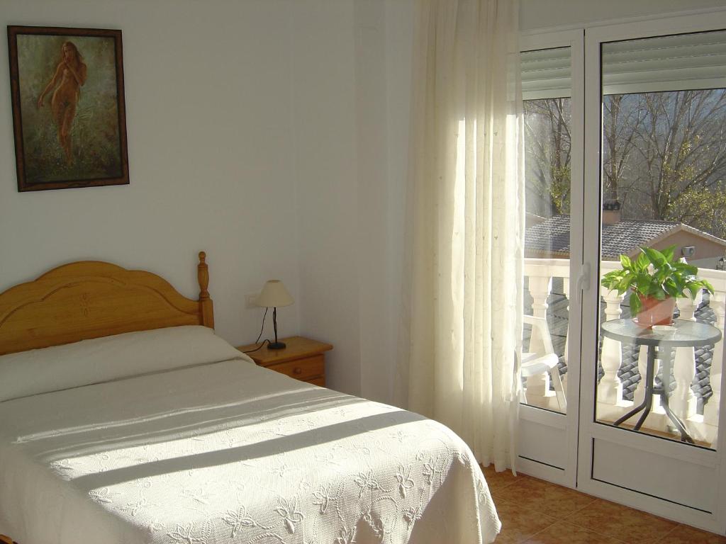 1 dormitorio con 1 cama y puerta corredera de cristal en Hostal D´Ernes en Alcalá del Júcar