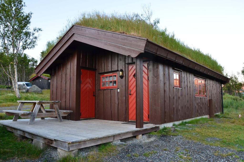 a small hut with a grass roof with a picnic table at Northern gate Besseggen - Cottage no 17 in Besseggen Fjellpark Maurvangen in Maurvangen