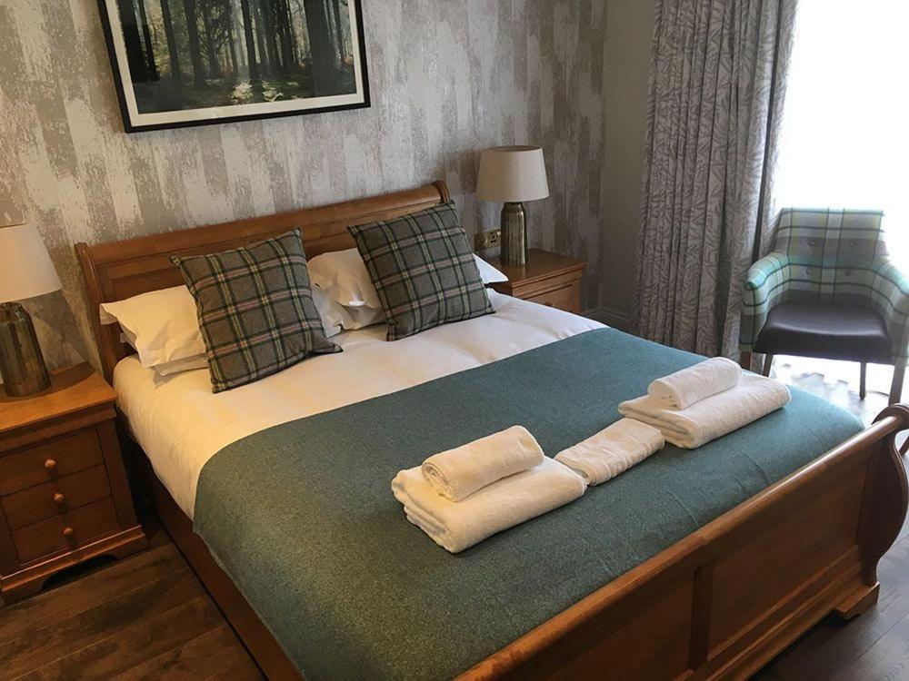 
a hotel room with a bed, chair, and nightstand at Charlcombe Inn in Bath
