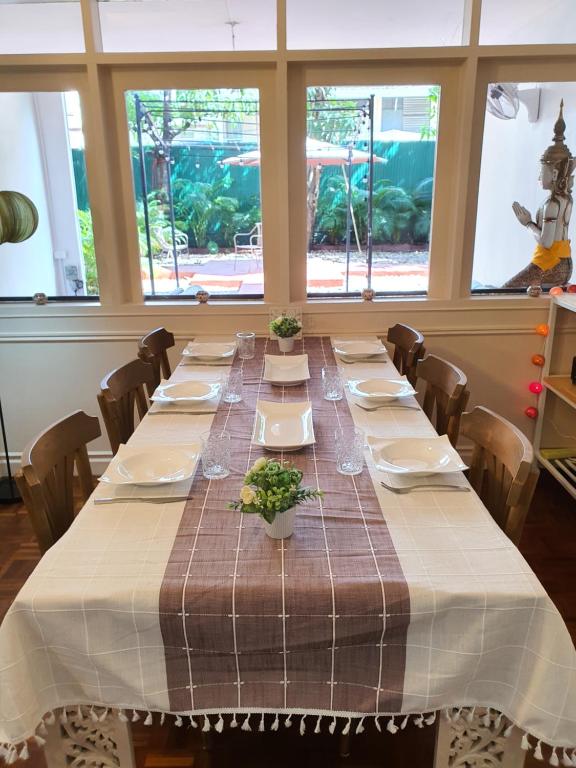 Una mesa larga en una habitación con una mesa puesta con platos. en Villa Thaï Sukhumvit Asok Nana, en Bangkok