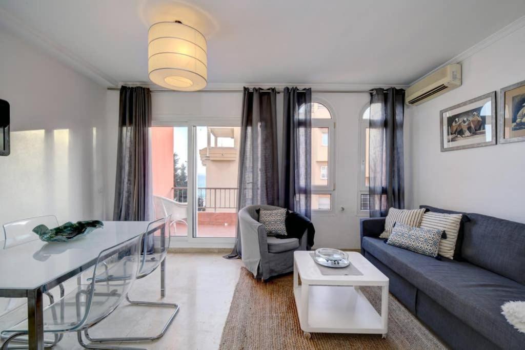 a living room with a blue couch and a table at Duplex con vistas al mar in La Línea de la Concepción