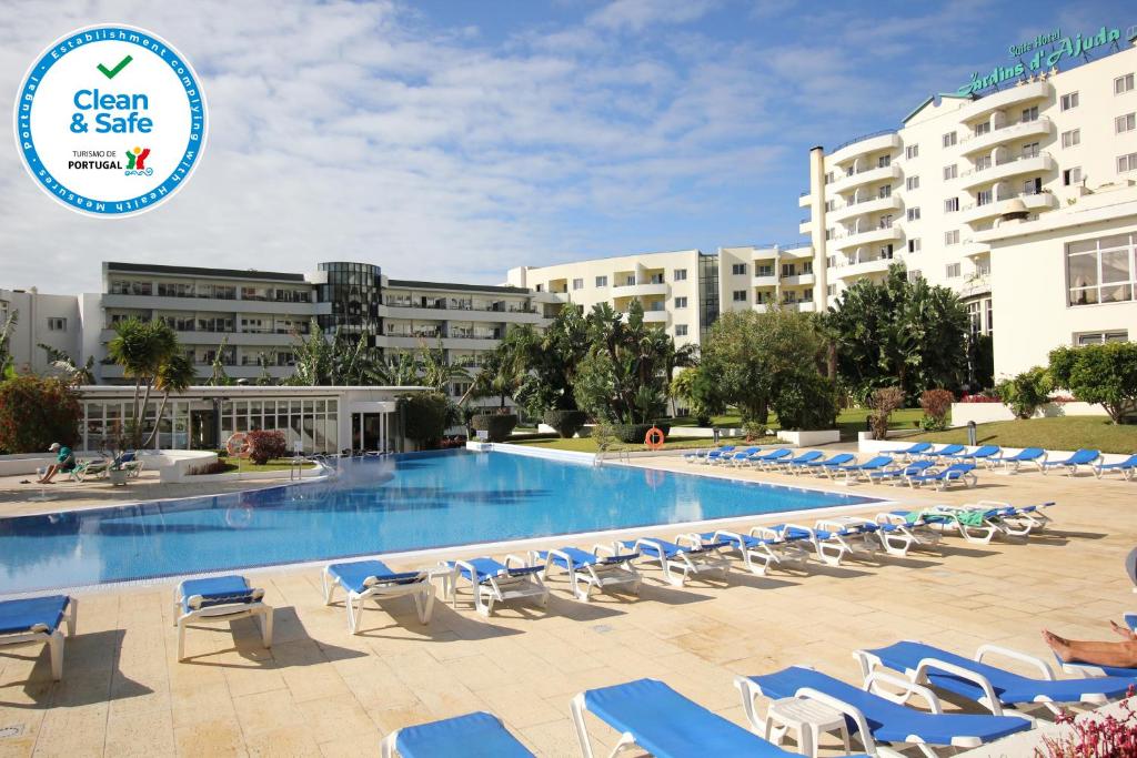 una piscina con tumbonas y un hotel en Suite Hotel Jardins Da Ajuda en Funchal