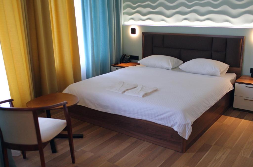 um quarto com uma cama branca com uma cadeira e uma mesa em EP Boutique Hotel em Vladivostok