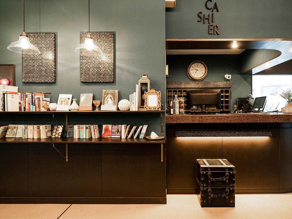 a coffee shop with a shelf of books and a clock at Hotel AreaOne Nobeoka in Nobeoka