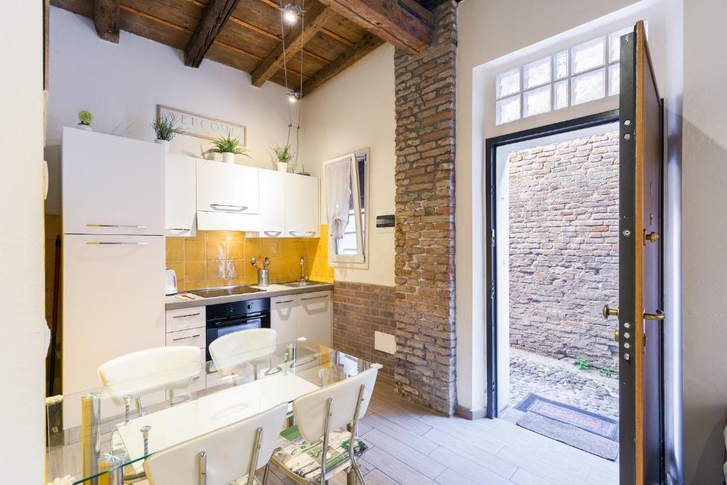 フェラーラにあるNel cuore di Ferraraの白いキャビネットとレンガの壁が備わるキッチン
