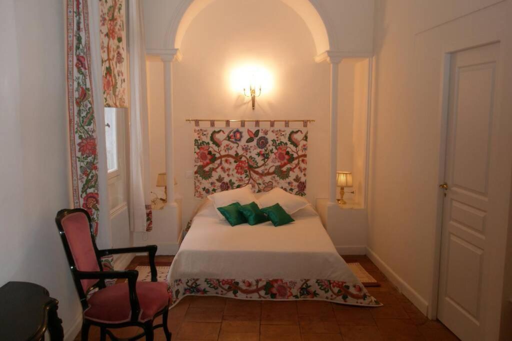 a bedroom with a bed with green pillows on it at Logis de Sainte-Scarbes in Toulouse