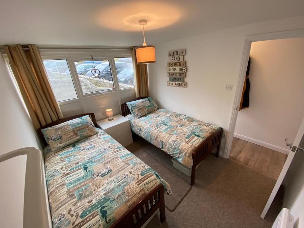 a bedroom with two beds and a window at Sunsets In Porthtowan, Cornwall Coastal Holidays in Porthtowan