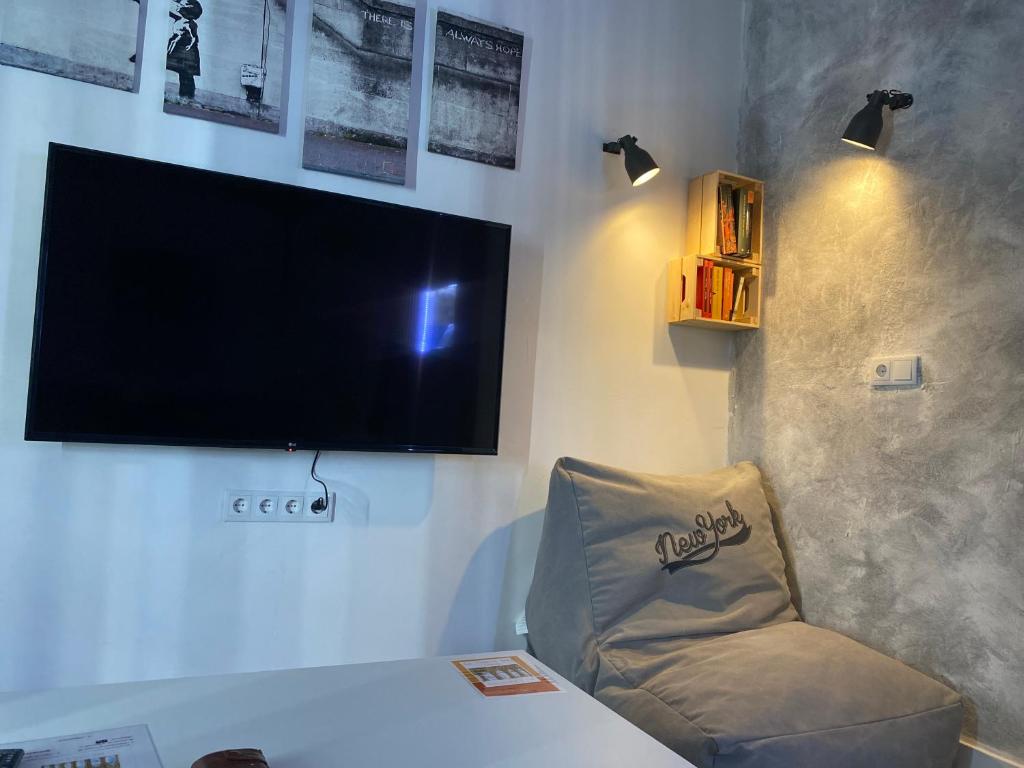 salon z telewizorem i krzesłem w obiekcie LA CUEVA DEL LOCO, Bretones 29 w mieście Sanlúcar de Barrameda