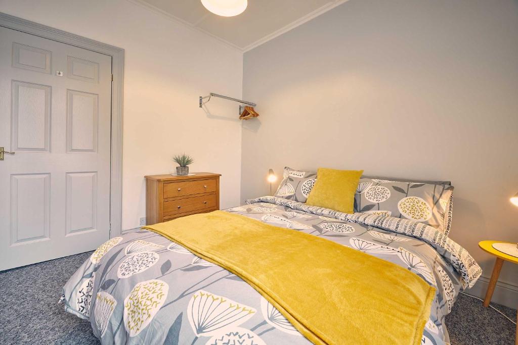 a bedroom with a bed with a yellow blanket on it at Host & Stay - Silverlinings in Seaton Delaval