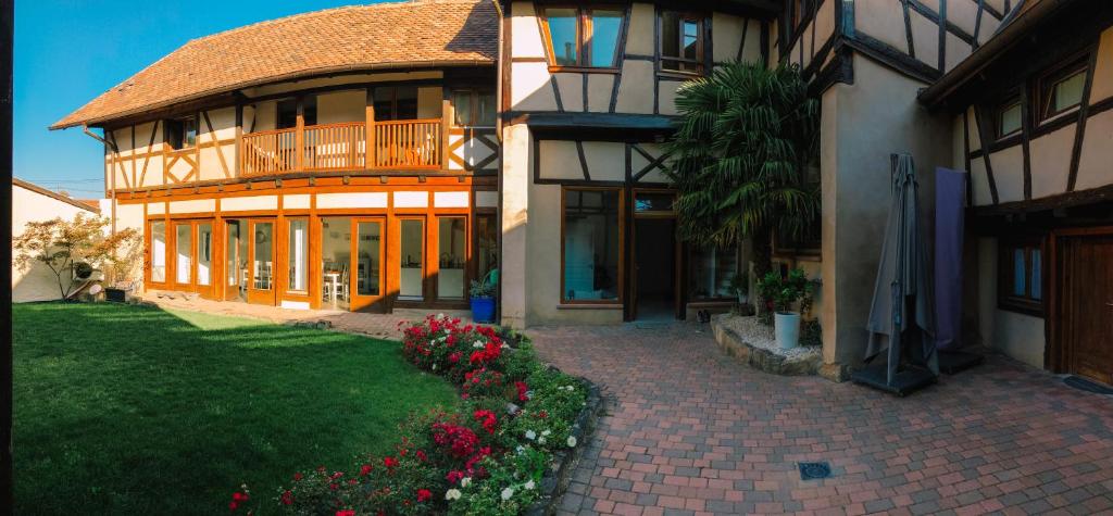 a large house with a balcony and a yard with flowers at Maison d'hôtes La Rose d'Alsace in Rosheim