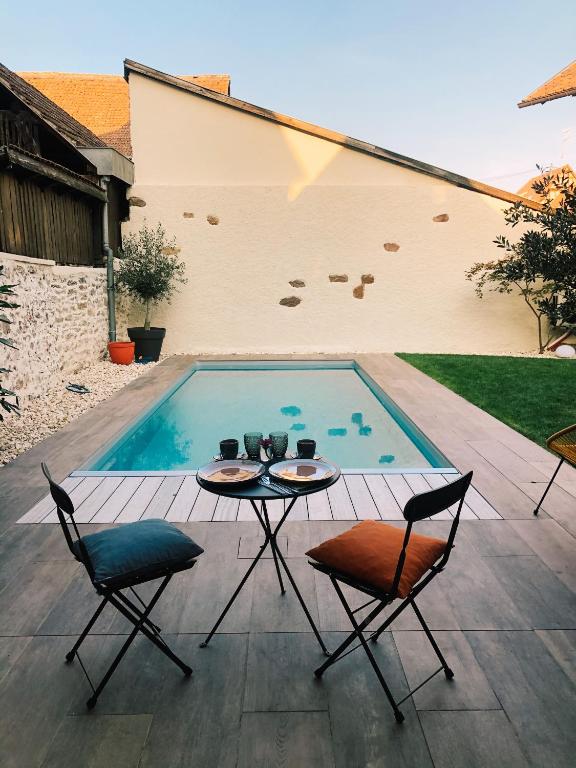 a patio with a table and chairs and a swimming pool at Maison d&#39;hôtes La Rose d&#39;Alsace in Rosheim