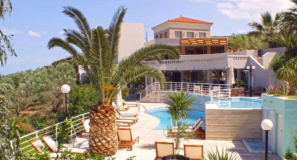 a house with a palm tree and a swimming pool at Pelagia Bay Hotel in Agia Pelagia