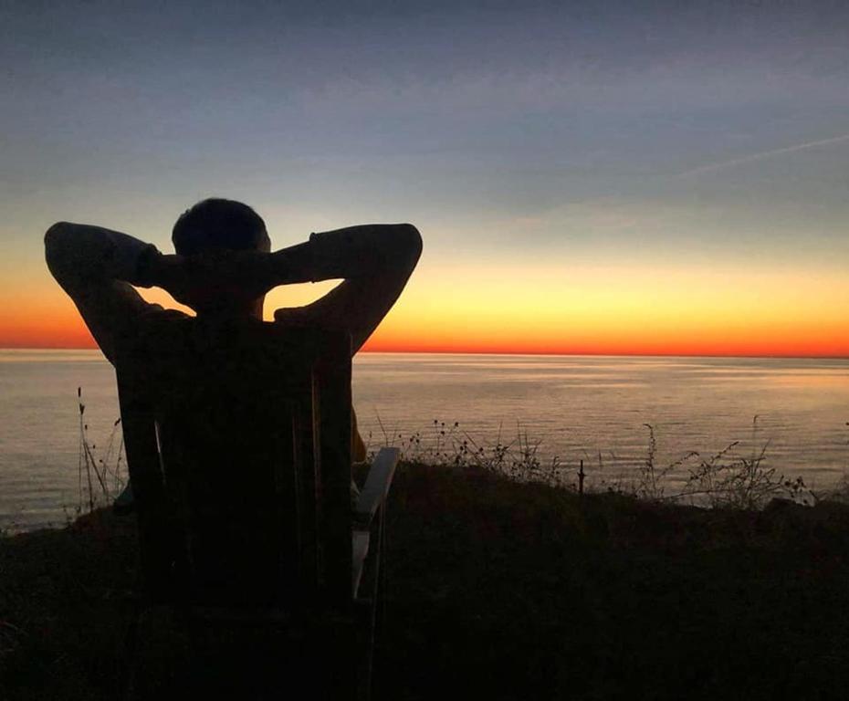 Eine Person, die auf einem Hügel sitzt und den Sonnenuntergang beobachtet. in der Unterkunft Sunset House in Ulmale