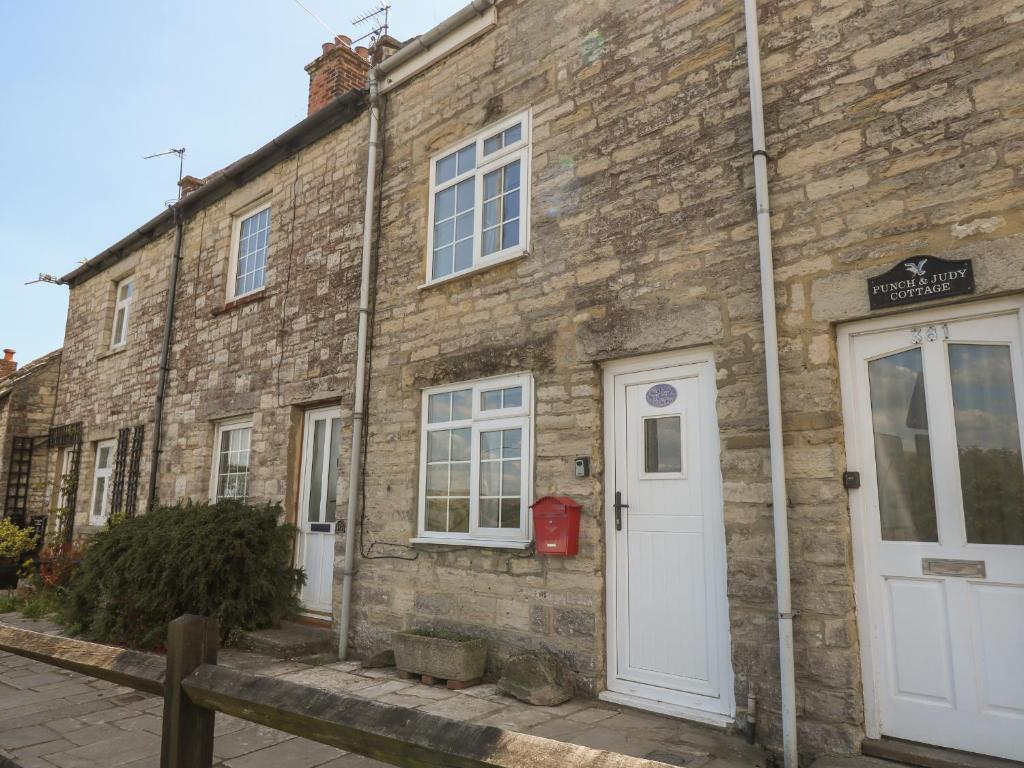 an old brick building with white doors and windows at Higgledy Piggledy Cottage in Swanage