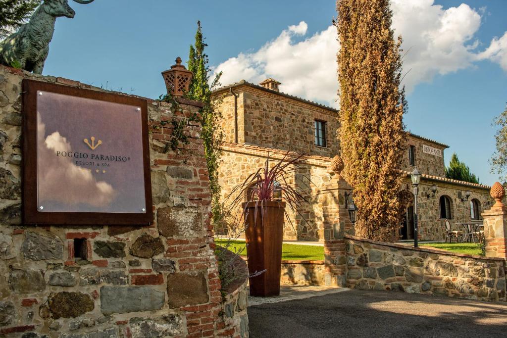 Montefollonico的住宿－Poggio Paradiso Resort & Spa，石头建筑前的标志