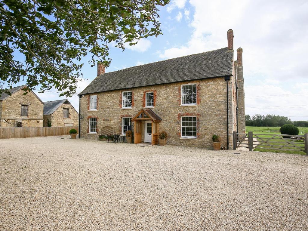an old brick house with a gravel driveway at Shifford Manor Farm in Witney