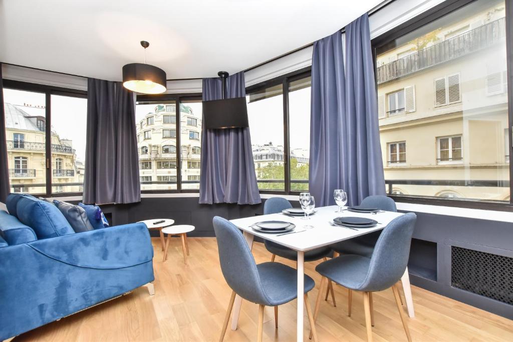 ein Wohnzimmer mit einem Tisch, Stühlen und Fenstern in der Unterkunft CMG Résidence Opéra in Paris