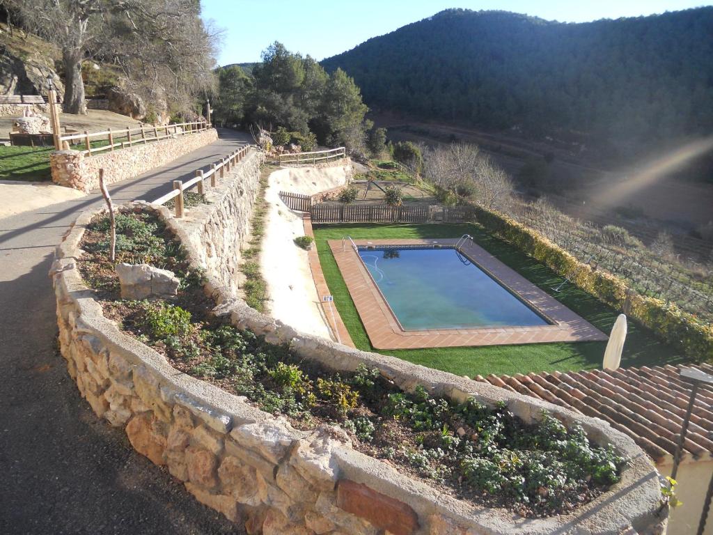 a stone wall with a swimming pool in a garden at Masía Puigadoll in Rodonyà
