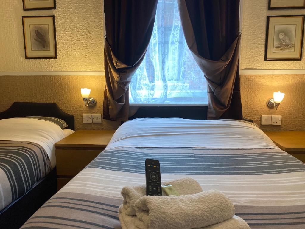 a bedroom with a bed with a remote control on it at Grange House Hotel in Blackpool