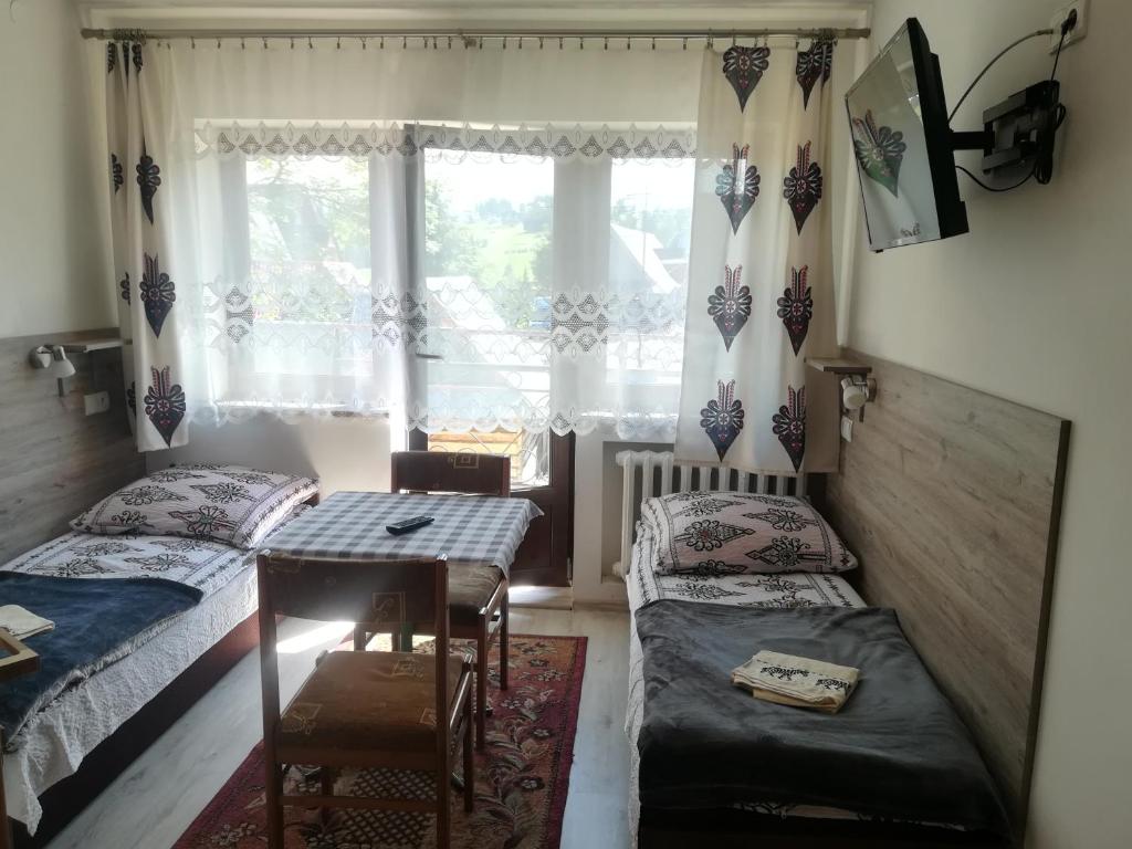a bedroom with two beds and a table and a window at Pokoje Gościnne U Babuni in Bukowina Tatrzańska