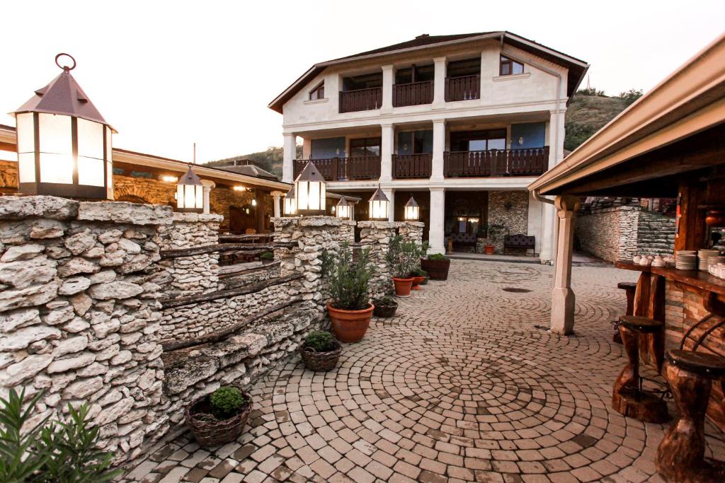 a building with a stone wall and a courtyard with potted plants at Vila Etnica in Trebujeni