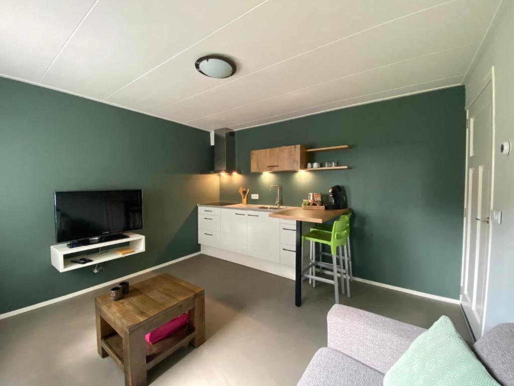 - une cuisine avec des murs verts, une table et une chaise dans l'établissement Appartement Duinweg, à Onstwedde