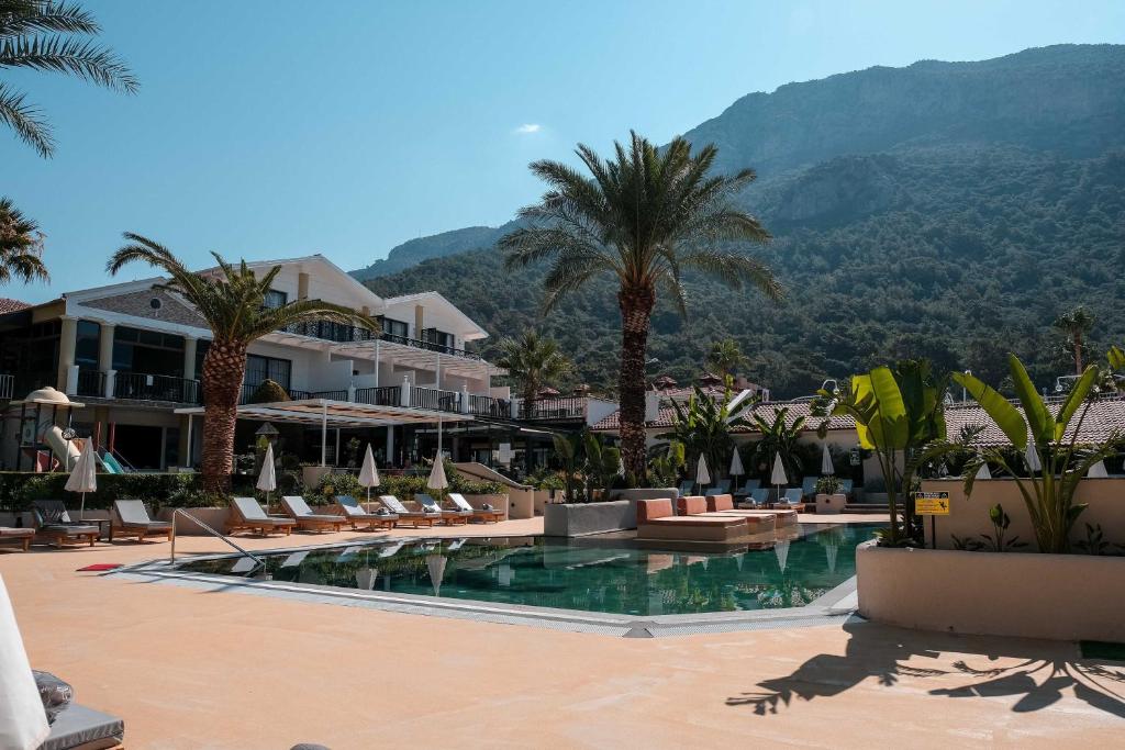 un complejo con piscina, palmeras y montañas en Hotel Karbel Sun, en Ölüdeniz