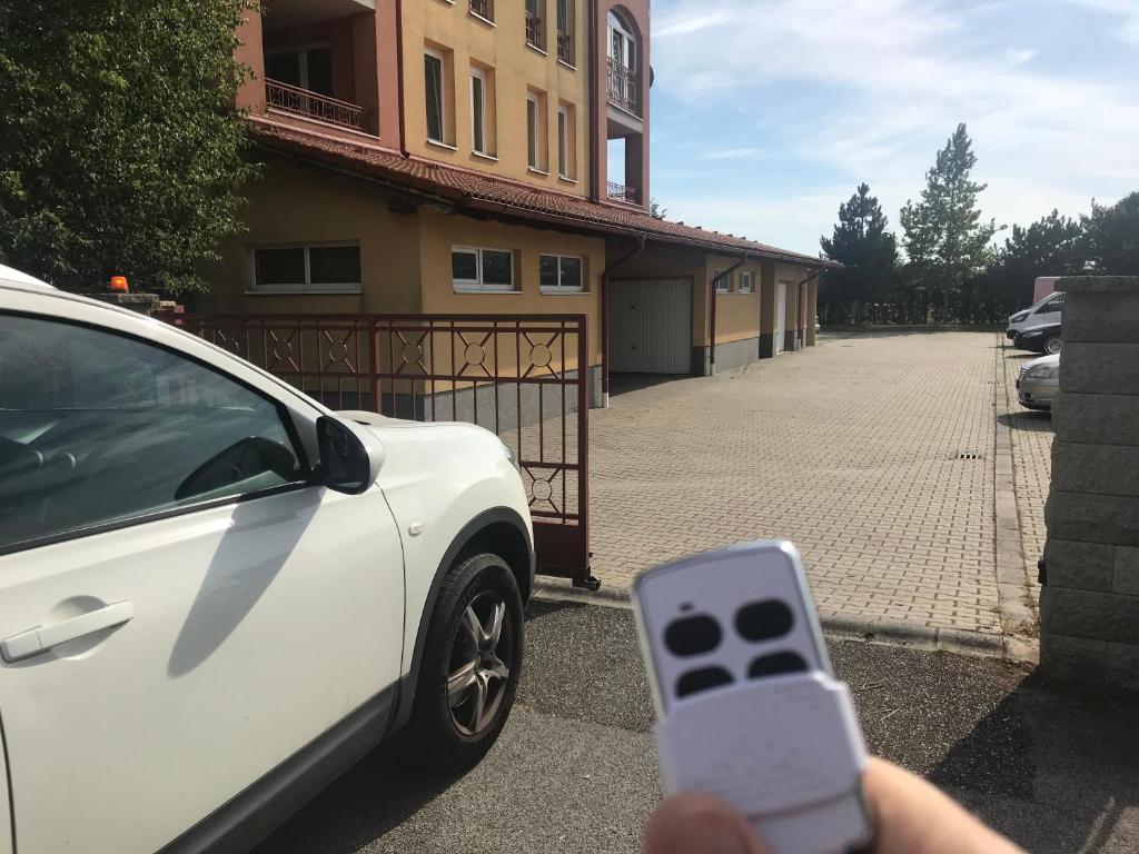 una persona sosteniendo un teléfono celular delante de un coche blanco en Réka Apartman, en Bük