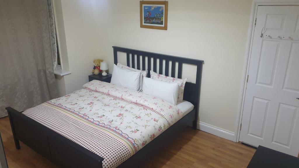 a bed with a black frame and white sheets and pillows at Guess bungalow wembley in London